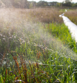 Water spraying from a leak in a long outdoor pipeline, symbolising hidden inefficiencies in fund administration.