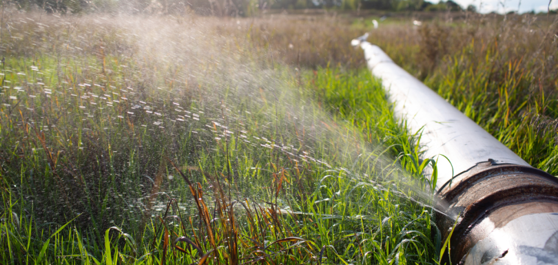 Water spraying from a leak in a long outdoor pipeline, symbolising hidden inefficiencies in fund administration.